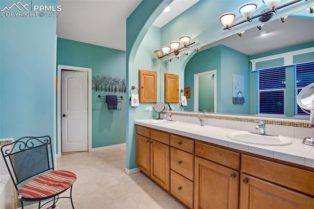 full bathroom with a sink, baseboards, and double vanity