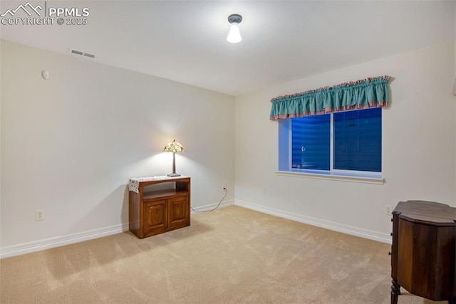 spare room featuring light carpet, visible vents, and baseboards