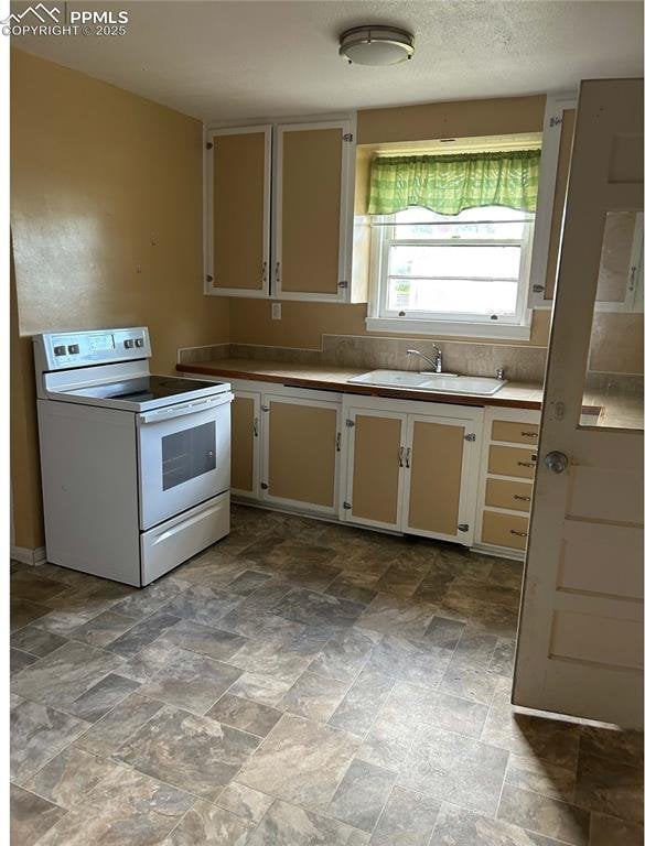 kitchen featuring a sink, white range with electric stovetop, and cream cabinets
