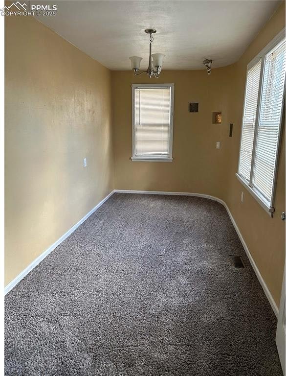spare room with visible vents, carpet flooring, baseboards, and an inviting chandelier