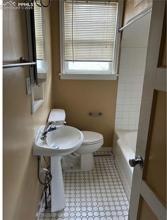 bathroom with tile patterned floors, walk in shower, a bathing tub, and toilet