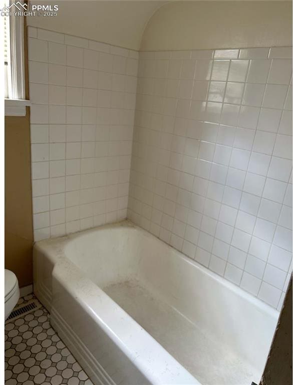 bathroom featuring tile patterned flooring, toilet, and a tub