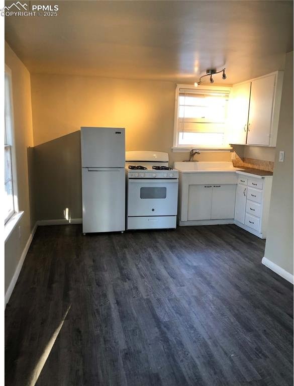 kitchen featuring a sink, white cabinetry, dark wood-style flooring, gas range gas stove, and freestanding refrigerator