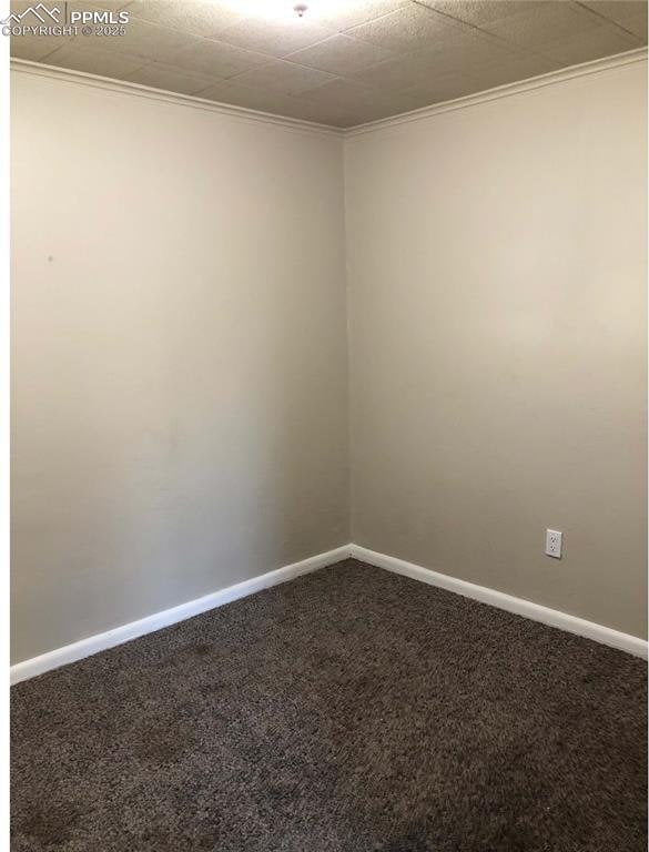 carpeted empty room featuring crown molding and baseboards