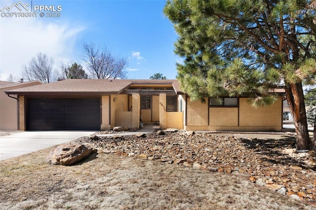 ranch-style house featuring a garage, concrete driveway, and stucco siding