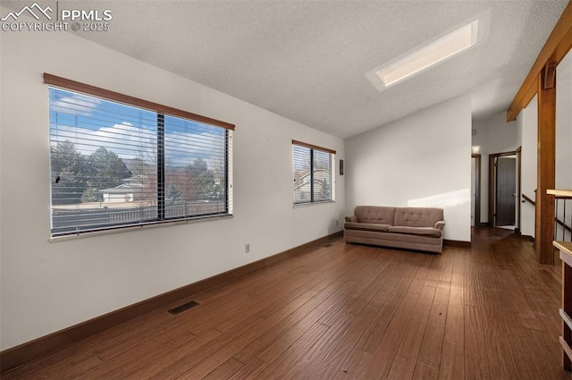 interior space featuring dark wood-style floors, lofted ceiling, visible vents, a textured ceiling, and baseboards