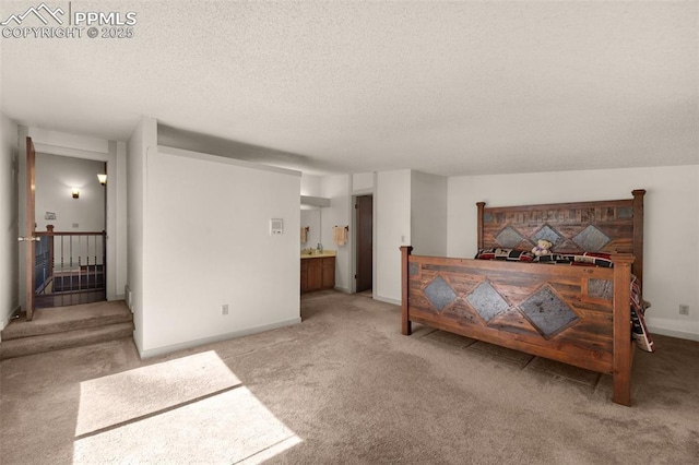 bedroom with carpet, ensuite bath, a textured ceiling, and baseboards