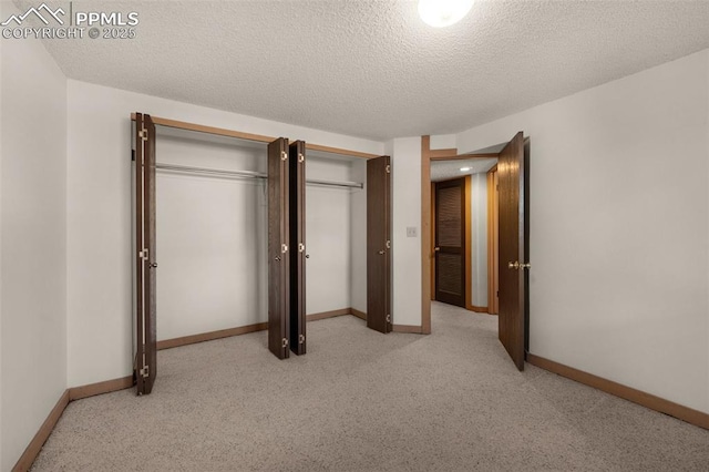 unfurnished bedroom with multiple closets, light colored carpet, a textured ceiling, and baseboards