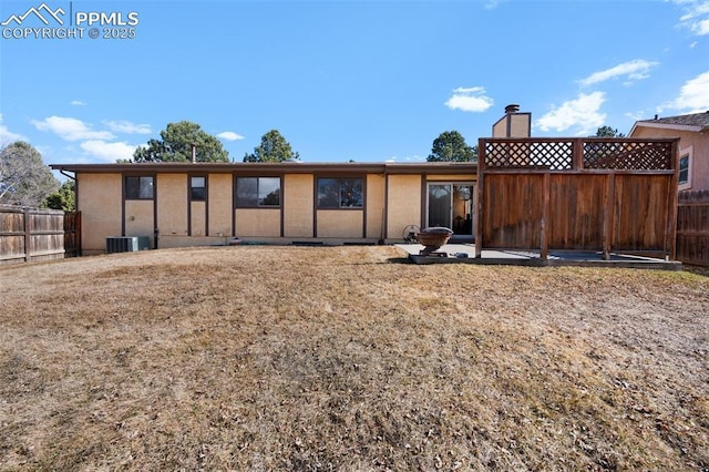 back of property with fence, a chimney, and central AC unit