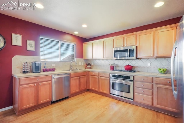 kitchen with recessed lighting, a sink, appliances with stainless steel finishes, light wood-type flooring, and backsplash