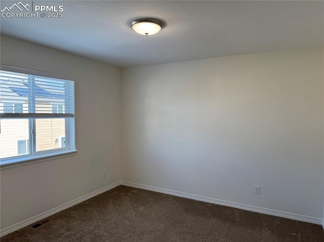 unfurnished room with dark colored carpet, visible vents, and baseboards