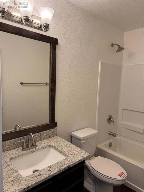 full bath featuring a textured wall, toilet, bathtub / shower combination, a textured ceiling, and vanity