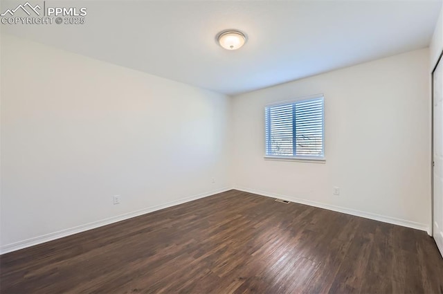 empty room with dark wood-style floors and baseboards