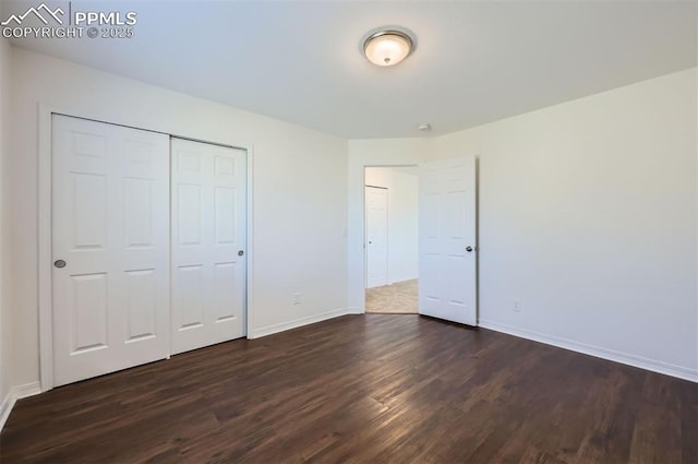 unfurnished bedroom featuring a closet, dark wood finished floors, and baseboards