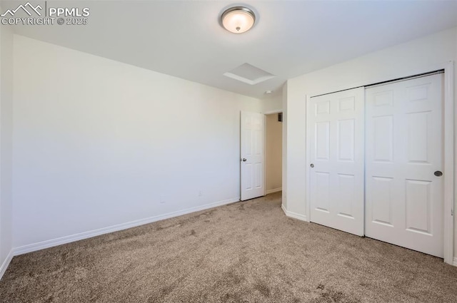 unfurnished bedroom featuring attic access, a closet, carpet flooring, and baseboards