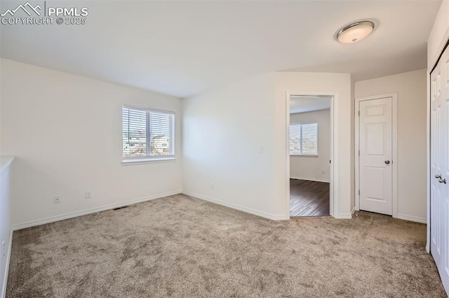 empty room with carpet flooring, plenty of natural light, visible vents, and baseboards