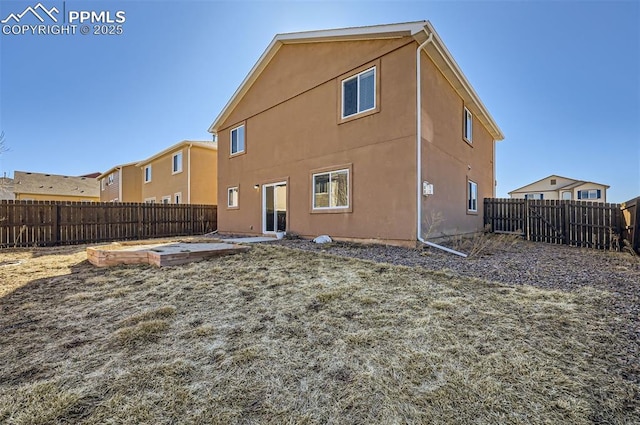 rear view of house with a fenced backyard, a vegetable garden, and stucco siding