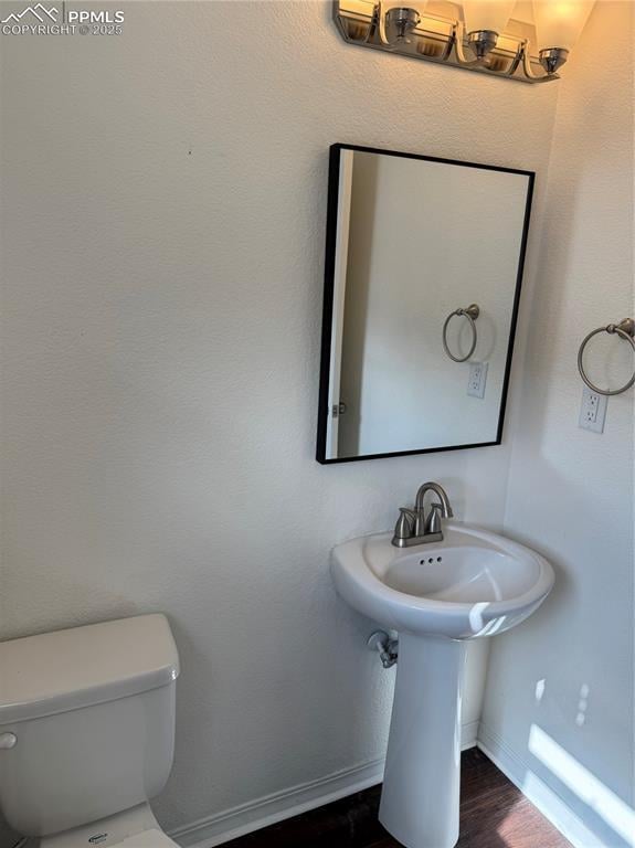 bathroom featuring baseboards, toilet, and wood finished floors