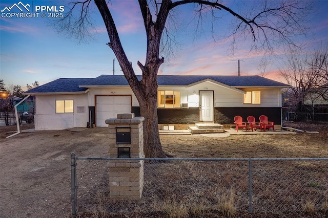 ranch-style house featuring driveway, a fenced front yard, a garage, and a shingled roof