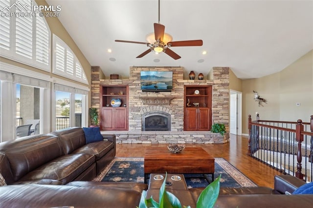 living area with ceiling fan, high vaulted ceiling, a stone fireplace, recessed lighting, and wood finished floors