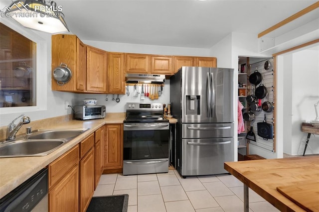 kitchen featuring light tile patterned flooring, under cabinet range hood, stainless steel appliances, a sink, and light countertops