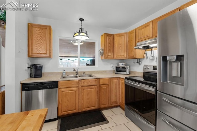 kitchen featuring a toaster, under cabinet range hood, stainless steel appliances, a sink, and hanging light fixtures