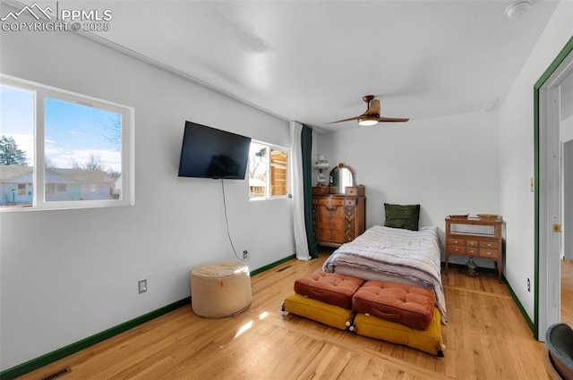 bedroom featuring ceiling fan, baseboards, and wood finished floors