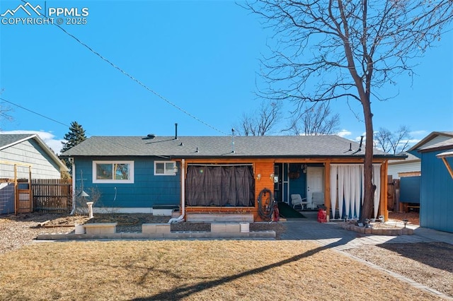 back of property with a shingled roof, fence, and a yard