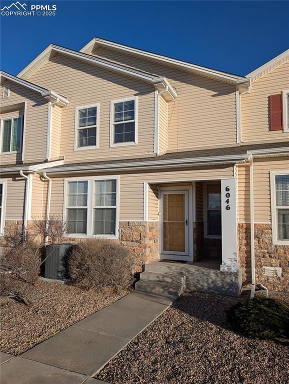 view of front facade with stone siding and central AC unit