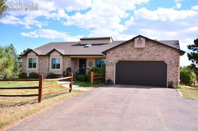 view of front facade with a fenced front yard, brick siding, driveway, and an attached garage