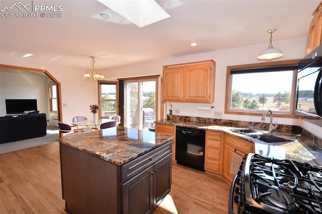 kitchen featuring a kitchen island, dark stone countertops, light wood-type flooring, black appliances, and a sink