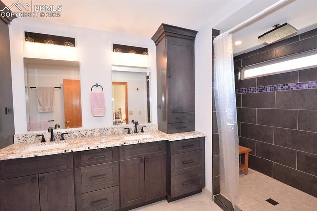 bathroom featuring a sink, a tile shower, and double vanity