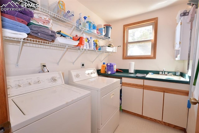 clothes washing area with cabinet space, a sink, and washing machine and clothes dryer