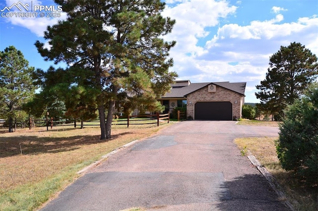 view of front of home featuring a garage, brick siding, fence, and aphalt driveway