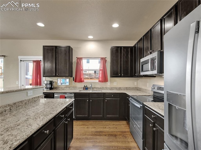 kitchen featuring light wood finished floors, appliances with stainless steel finishes, a sink, and a healthy amount of sunlight