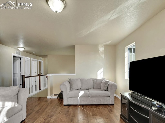 living area with hardwood / wood-style flooring, baseboards, visible vents, and a textured ceiling