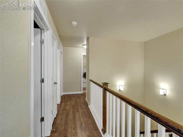 corridor with dark wood-type flooring, washer / clothes dryer, and baseboards