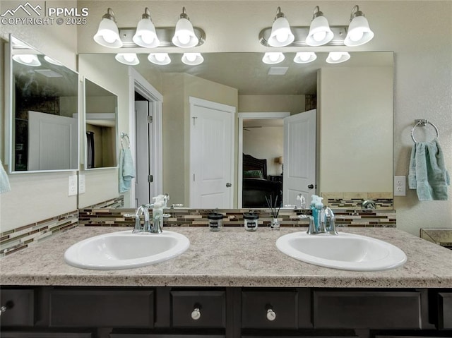 full bathroom with a sink, backsplash, and double vanity