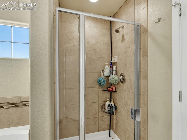 bathroom with a garden tub, a textured wall, and a shower stall