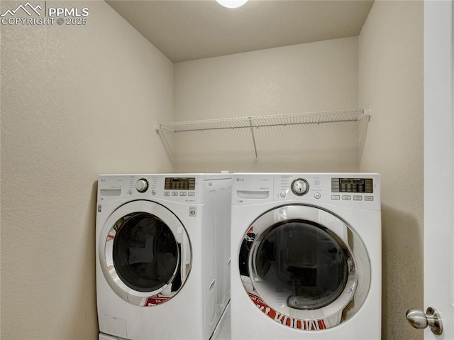 laundry room featuring laundry area, a textured wall, and washing machine and clothes dryer