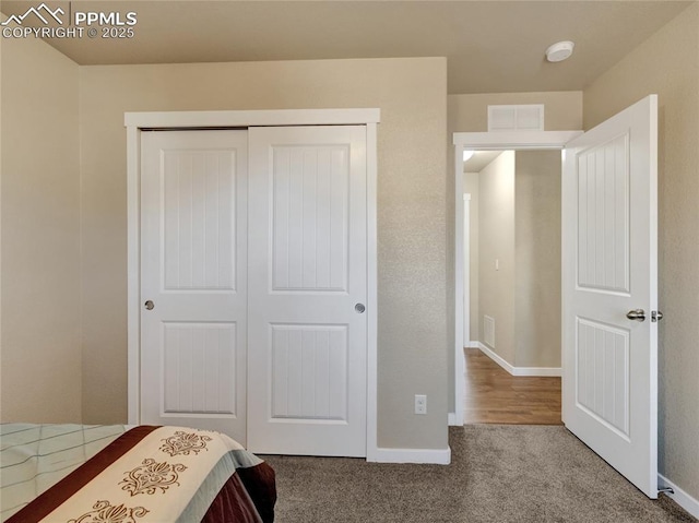 bedroom featuring carpet floors, visible vents, baseboards, and a closet