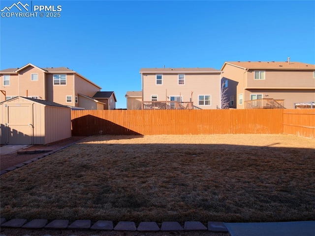 view of yard featuring an outbuilding, a fenced backyard, a residential view, and a shed