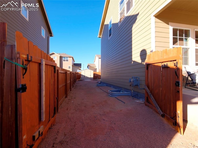 view of side of property with a fenced backyard, a residential view, an outbuilding, a patio area, and a shed