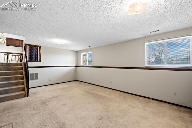 below grade area with carpet flooring, a textured ceiling, and visible vents