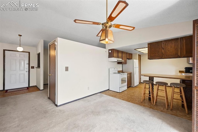 kitchen featuring ceiling fan, under cabinet range hood, light carpet, and white appliances