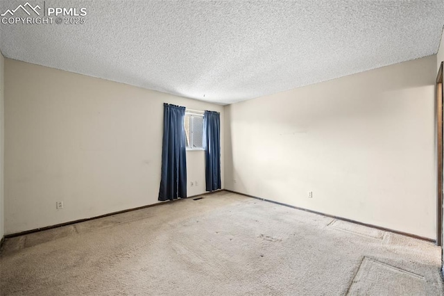 spare room featuring baseboards, carpet flooring, and a textured ceiling