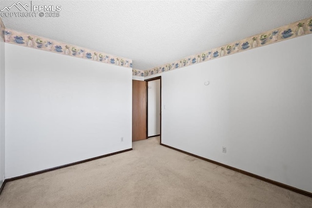 empty room featuring light colored carpet and baseboards