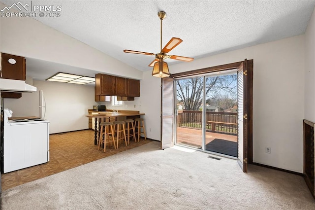 interior space featuring visible vents, white electric range, under cabinet range hood, a ceiling fan, and vaulted ceiling