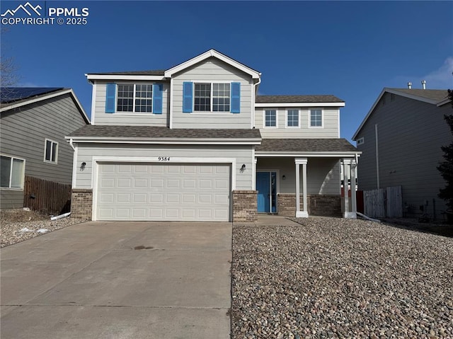 view of front of house with brick siding, driveway, an attached garage, and fence