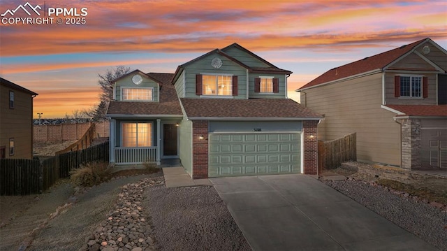 traditional-style home with brick siding, fence, driveway, and an attached garage